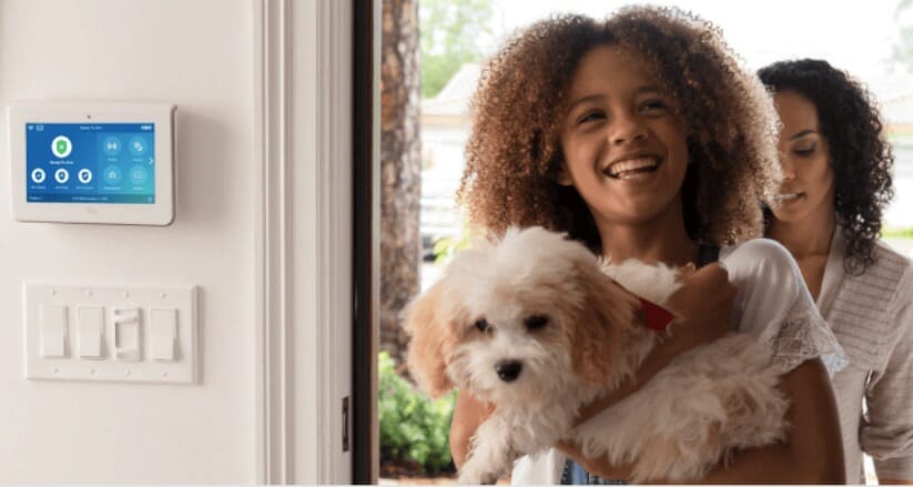 mother and daughter holding a puppy and the adt installed at the wall
