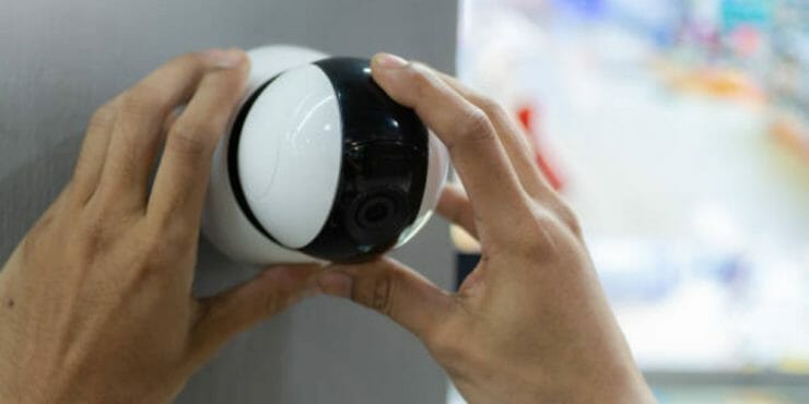 man mounting a security camera on the wall