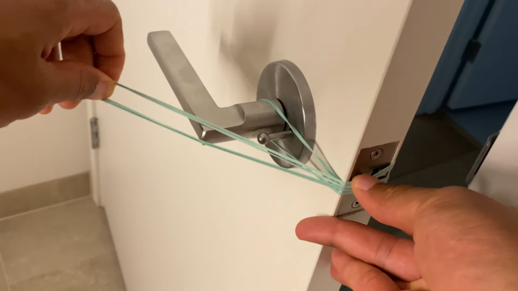 man putting rubber band on the doorknob